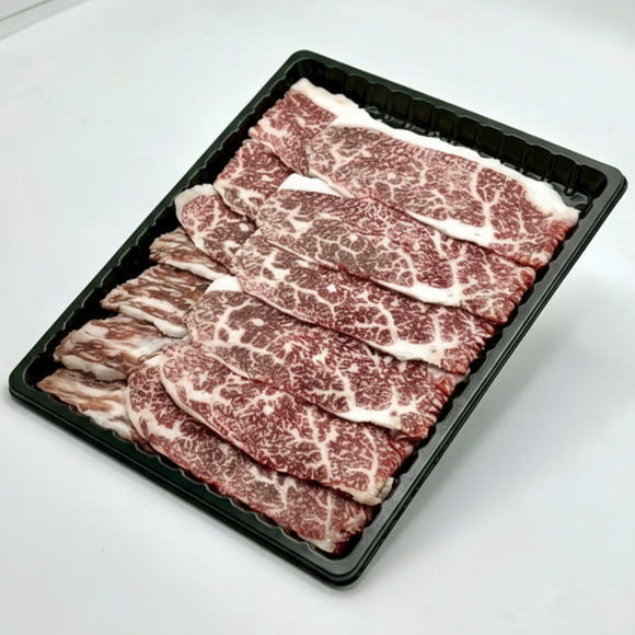 Raw beef slices on a black tray with a white background